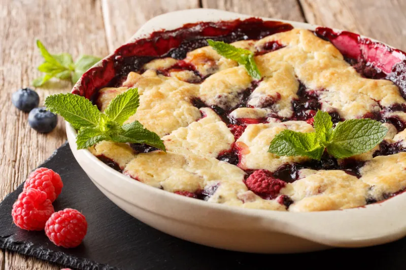 summer berry cobbler of raspberries and blueberries close up in a dish baking dish on the table horizontal