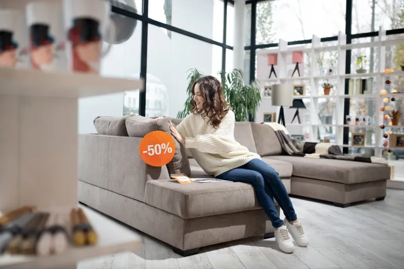 interested in new sofa woman in white shirt and jeans looking interested