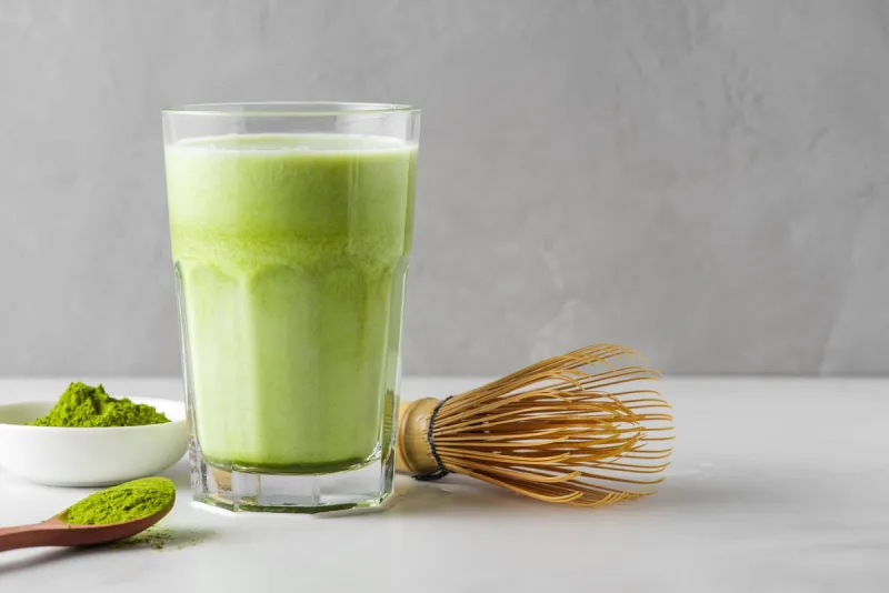 matcha green tea iced latte with matcha powder and bamboo whisk cold refreshment summer drink vegan food