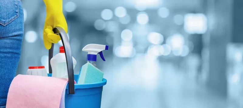 the concept of cleaning service a cleaning lady is holding a bucket of cleaning products on a blurred background