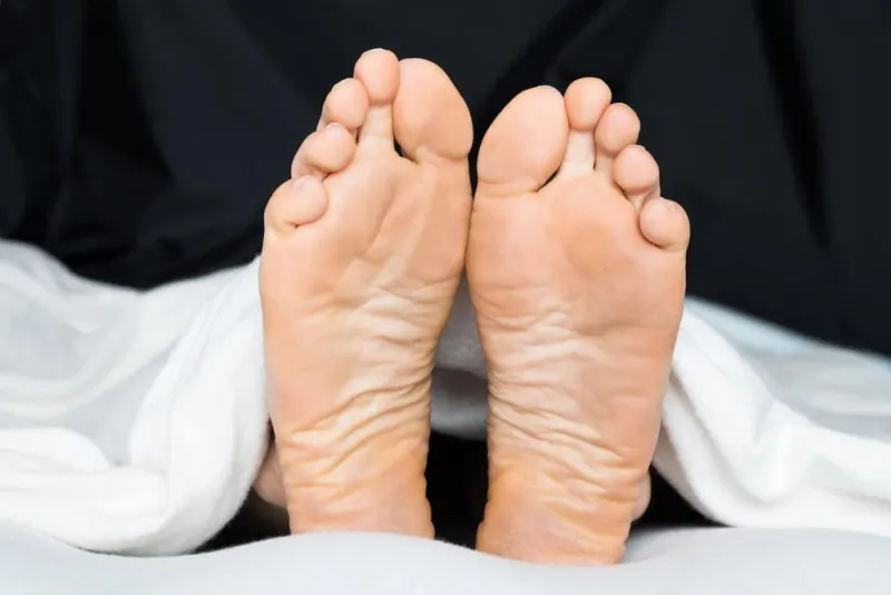 gros plan des pieds d'une personne sous la couverture sur le lit