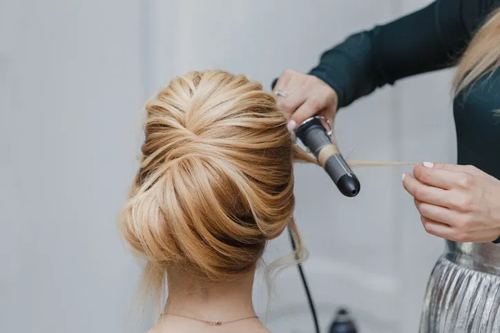 closeup of professional hairdresser hands doing beauty hairstyle a-la french twist