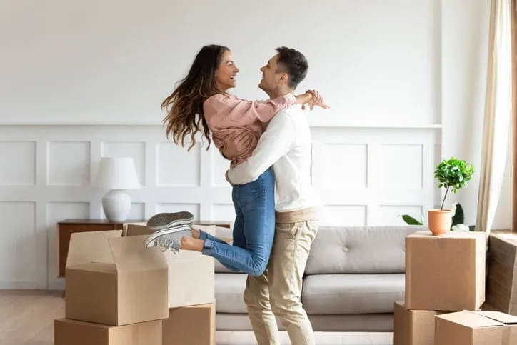 overjoyed caucasian husband hold carry swirl happy wife excited to move in new home together, smiling young couple dancing in living room have fun on relocation day in apartment, ownership concept