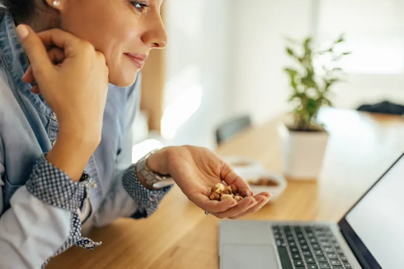 healthy lifestyle beautiful woman eating nuts for a snack at work