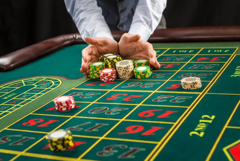 picture of a green table and betting with chips man hand over casino chips - bet close up