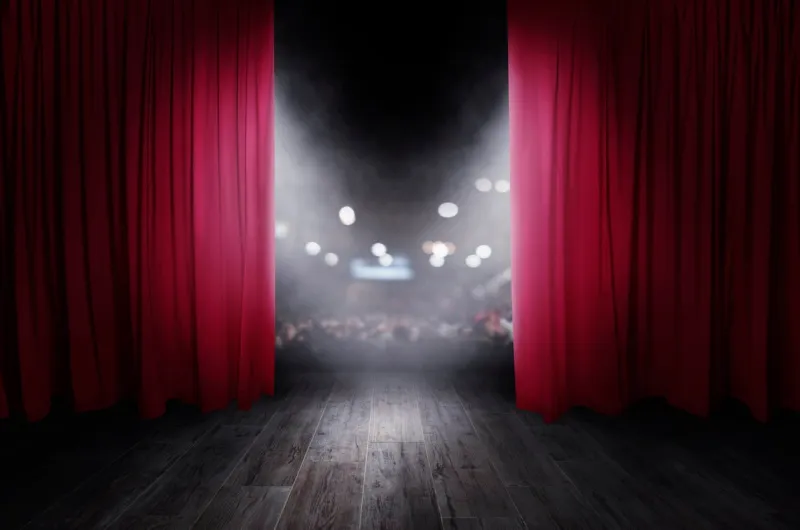 the red curtains of the stage are opening for the theater show