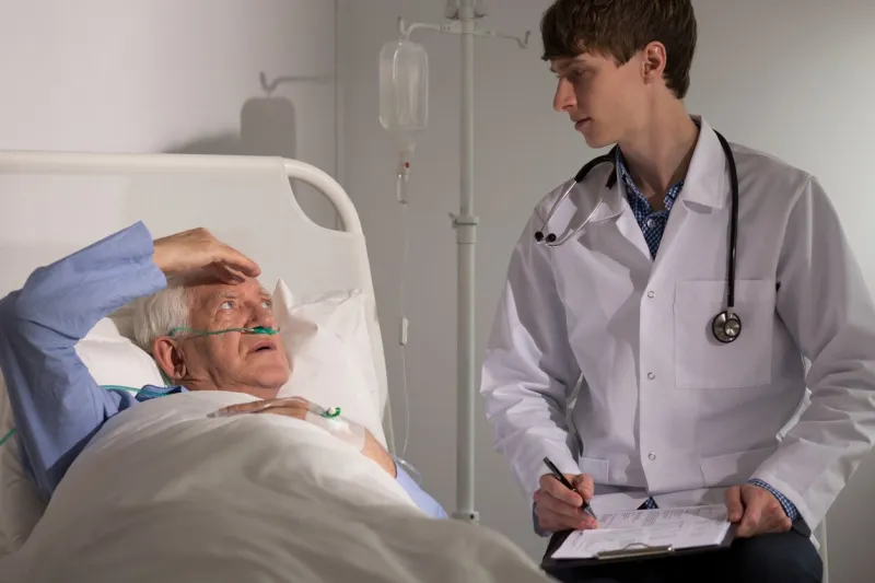 sick older man with headache complaining to his physician