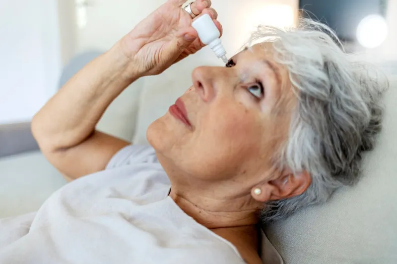 photo of a senior woman putting eye drop, closeup view of an elderly person using a bottle of eyedrops in her eyes a sick old woman suffering from irritated eye, optical symptoms health concept concept of eye treatment, vision improvement, poor eyesight