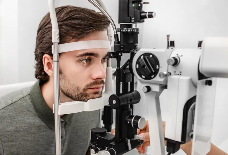 adult man getting an eye exam at ophthalmology clinic checking retina of a male eye close-up