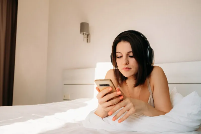 young girl of caucasian appearance being in bedroom listens to music using headphones listen to your favorite music or watch news in morning at home