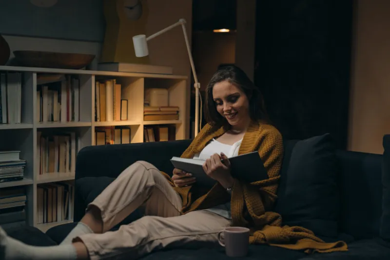 woman reading book at home evening scene