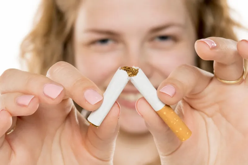 young woman breaking cigarette in half, smiling confidently symbolizing quitting smoking, health awareness, and personal triumph over addiction