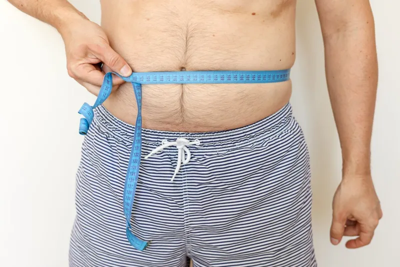 man measures his fat belly with measuring tape and shows thumb up concept of weight loss, health problems of obese people controlling eating and active lifestyle world obesity day