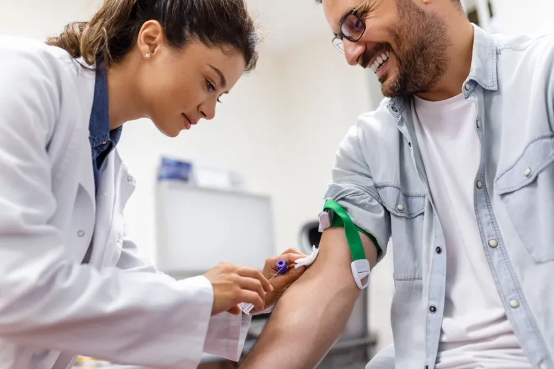 preparation for blood test by female doctor medical uniform on the table in white bright room nurse pierces the patient's arm vein with needle blank tube