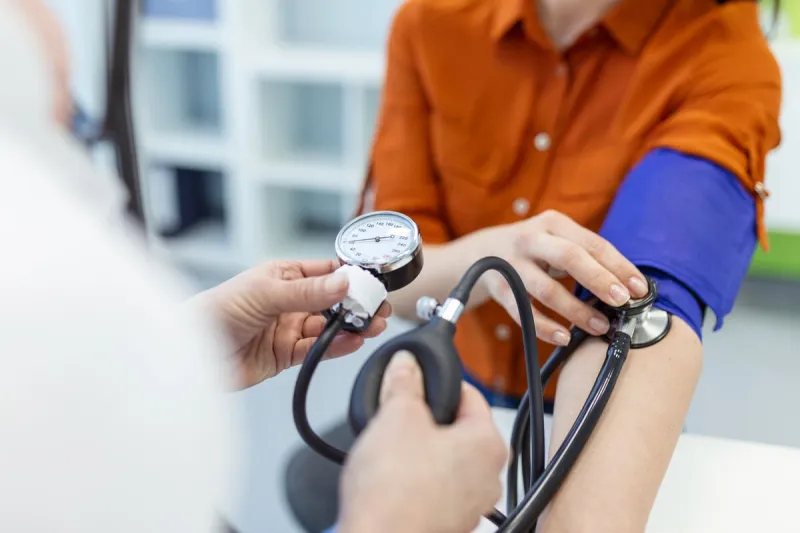 doctor using sphygmomanometer with stethoscope checking blood pressure to a patient in the hospital