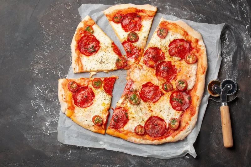 home made pizza with chorizo, mozzarella and tomatoes on table top view