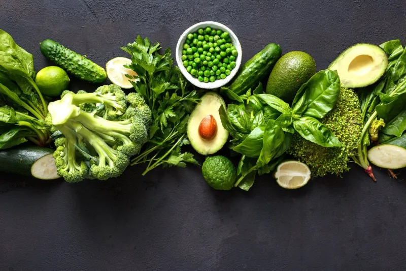 raw healthy food clean eating vegetables  cucumber, alfalfa, zucchini, spinach, basil, green peas, dill, parsley, avocado, broccoli, lime on dark stone background, top view
