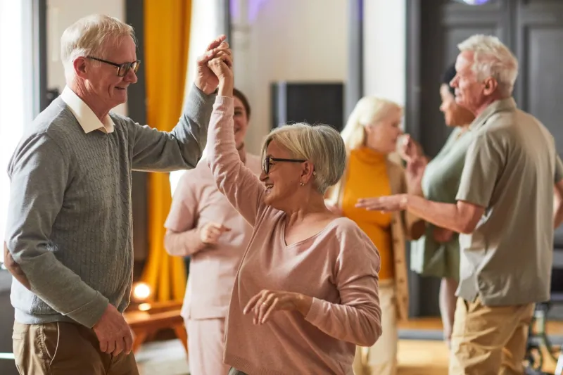 group of smiling senior people dancing while enjoying activities in retirement home, copy space