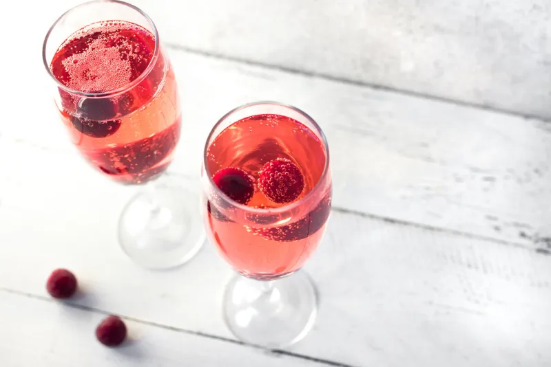 kir royal champagne cocktail on white, copy space flute glasses with berry sparkling champagne drink for celebrating or chilling