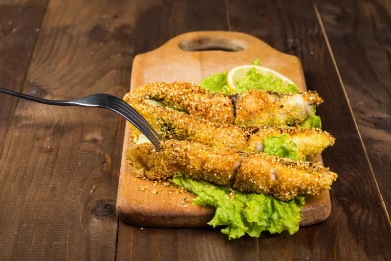 poisson frit sur une planche de bois avec de la laitue se bouchent