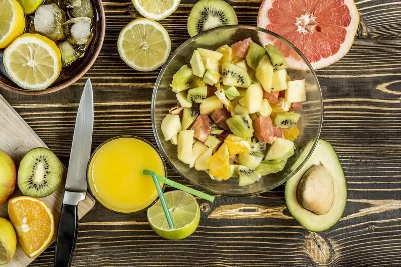 salade de fruits d'agrumes serviette de planche de couteau de jus d'orange sur la vue de dessus de table en bois foncé