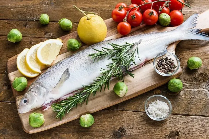 poisson frais avec des légumes sur une planche de bois