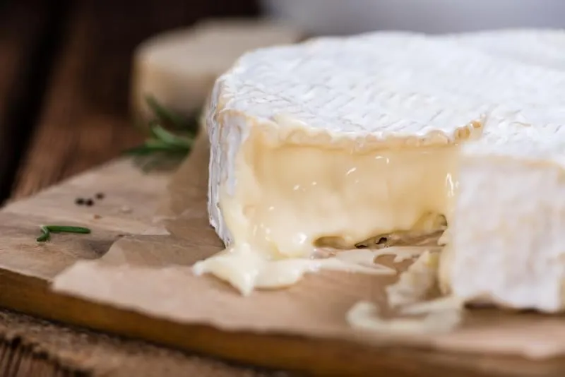portion de camembert crémeux (gros plan détaillé) sur fond en bois rustique