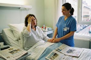 Femme qui se réveille dans une chambre d'hôpital, une infirmière à ses côtés