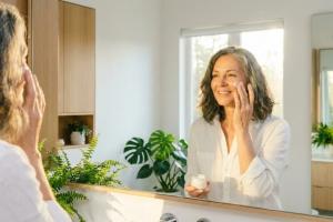 Prompt 1: Une femme rayonnante d'une cinquantaine d'années sourit doucement devant un miroir baigné 