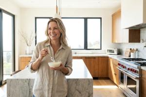 Femme qui mange un yaourt dans sa cuisine