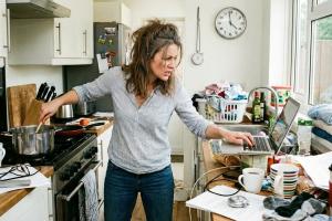 Photo d'une femme qui cuisine d'une main et qui travaille sur l'ordinateur de l'autre