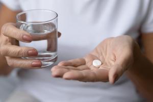 personne qui prend une aspirine avec un verre d'eau