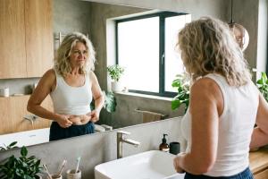 femme âgée de 50 ans environ qui se regarde dans le miroir