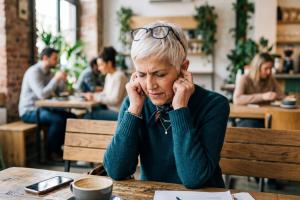personne qui se touche les oreilles car elle souffre d'acouphènes
