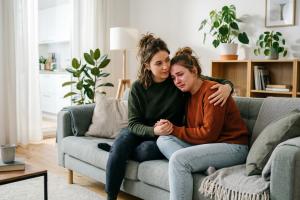 2 personnes sur un canapé, l'une soutient l'autre