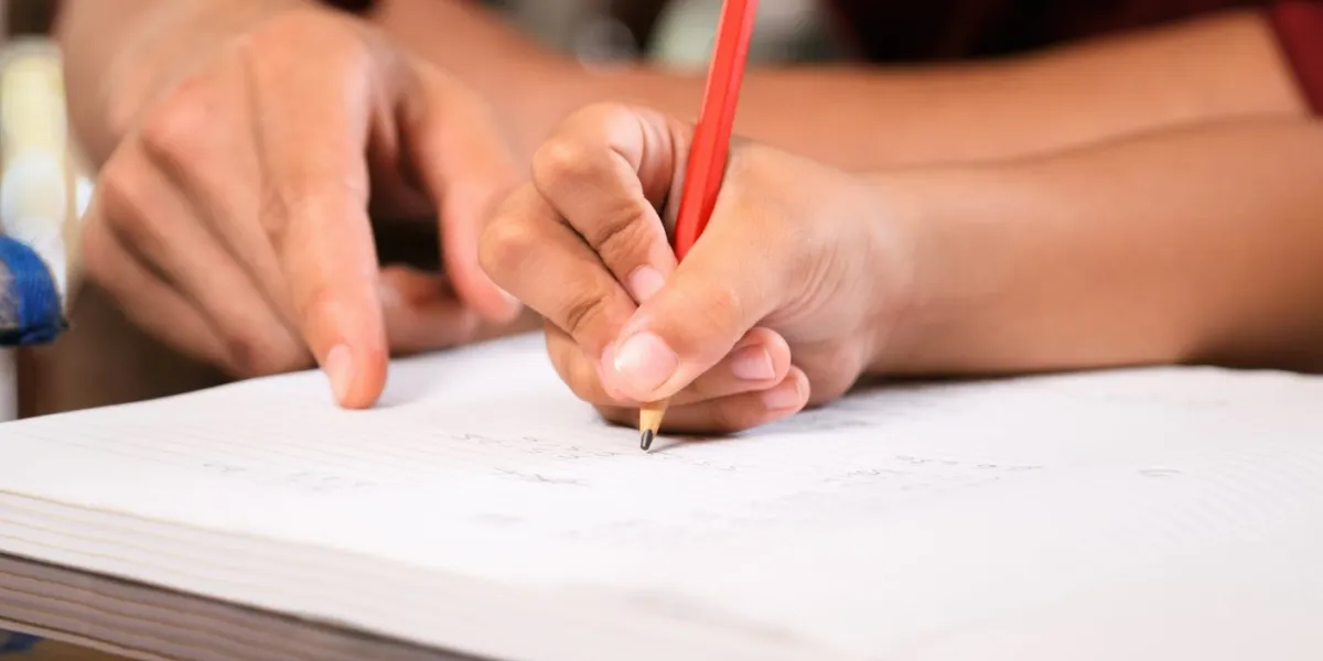 dad helping elementary age daughter with school homework concept of parent spending time with family close-up of exercise book, pencil, hand writing on paper