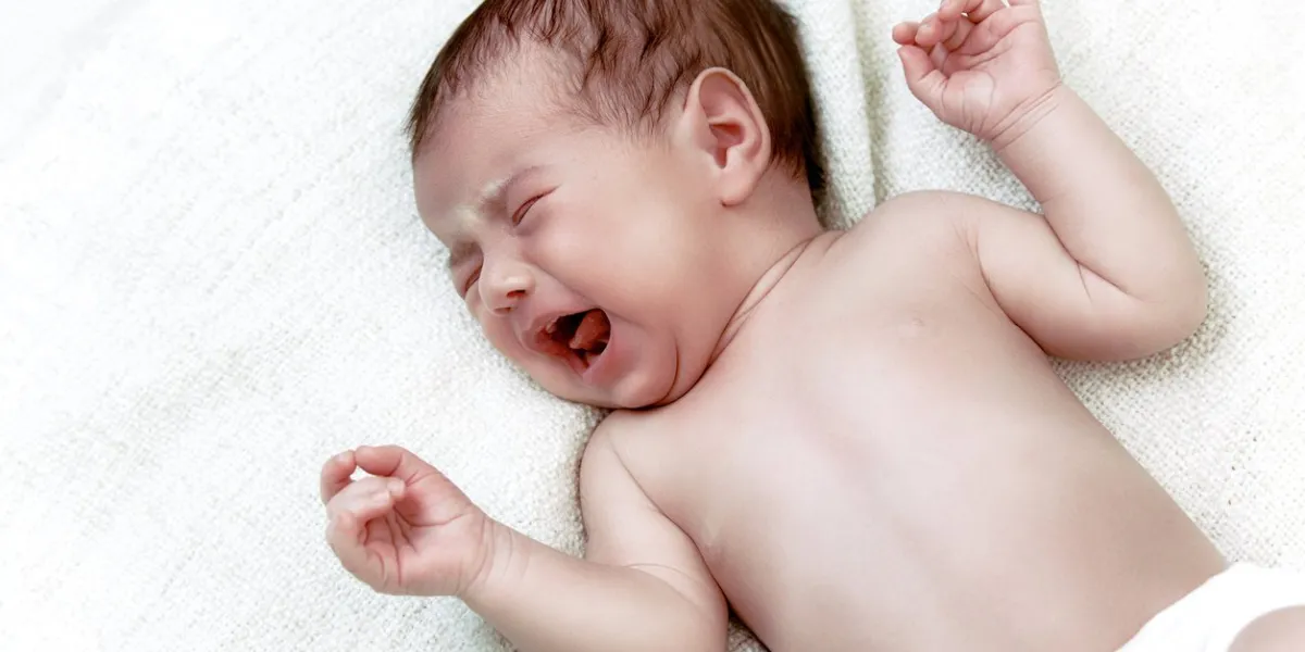 cute newborn baby crying in white bad