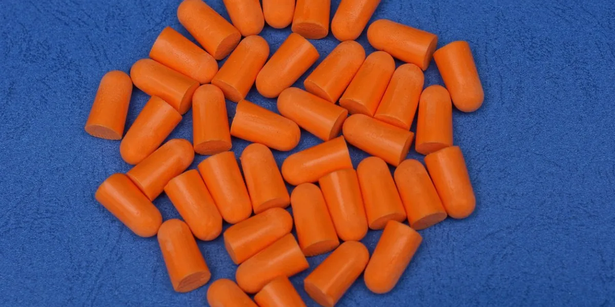 heap of red plastic earplugs on a blue table