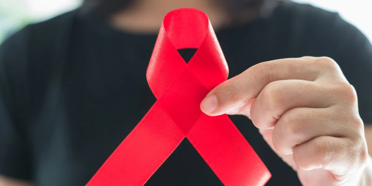 aids red ribbon on woman's hand support for world aids day and national hiv aids and aging awareness month concept