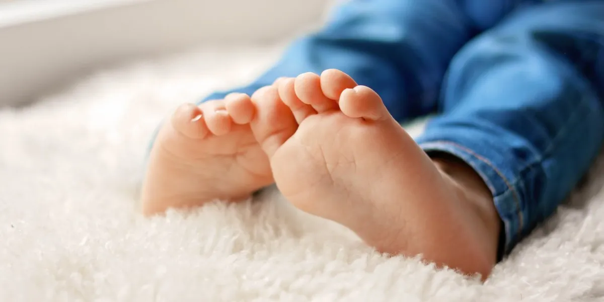 cozy holidays at home close up photo of little child barefooted feet sitting on white furry blanket at window winter season lifestyle leisure time sweet childhood copy space