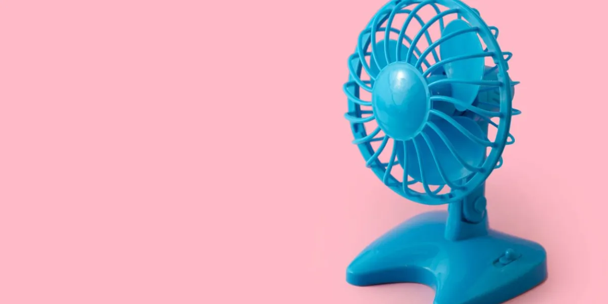 electric blue plastic fan isolated on pink background