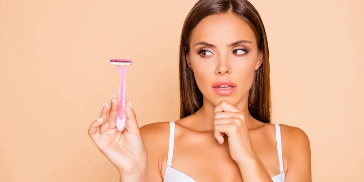 wax or shave close up portrait of thinking lady look aside on safety razor she isolated on pastel beige background with her worried face