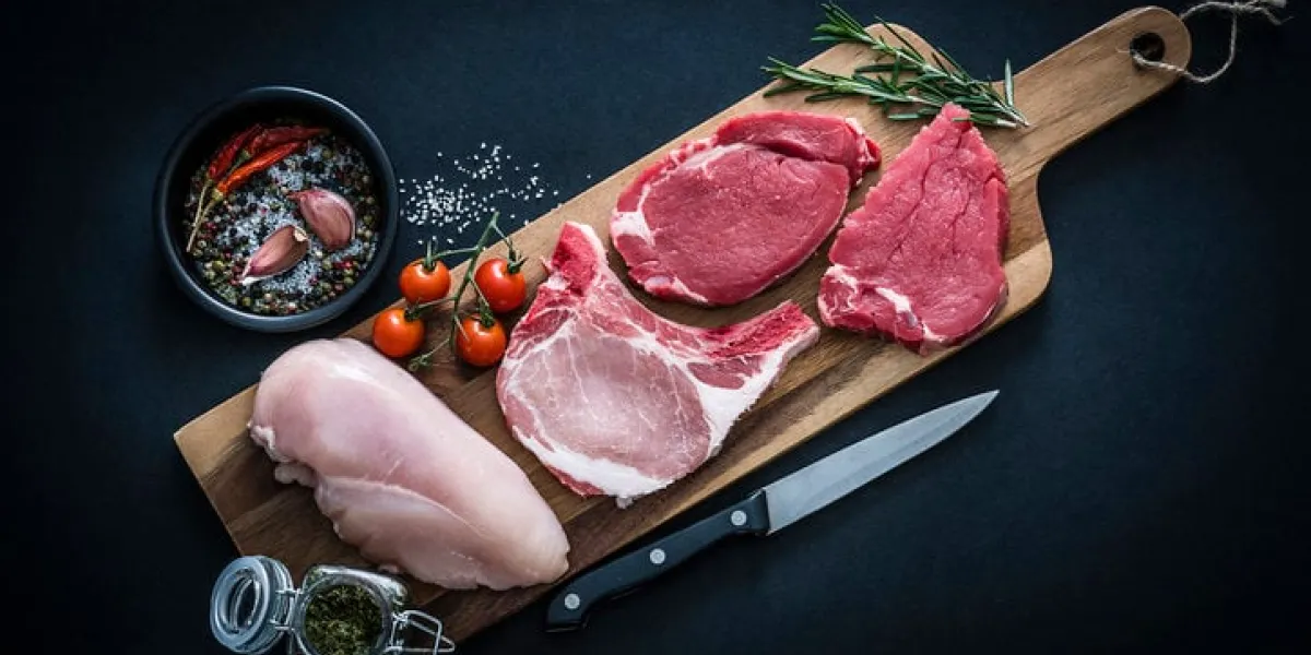 raw meat assortment - beef, chicken and pork chops shot from above on dark background