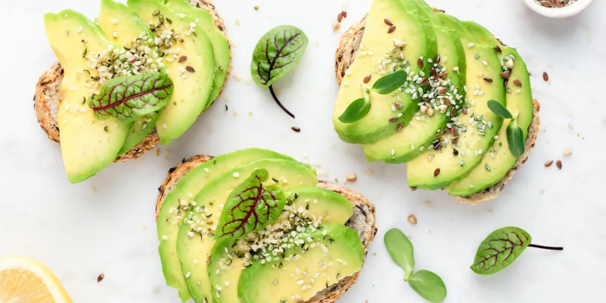 avocado slices with seeds and micro greens on toasted bread on white background healthy vegan vegetarian avocado toasts, top view