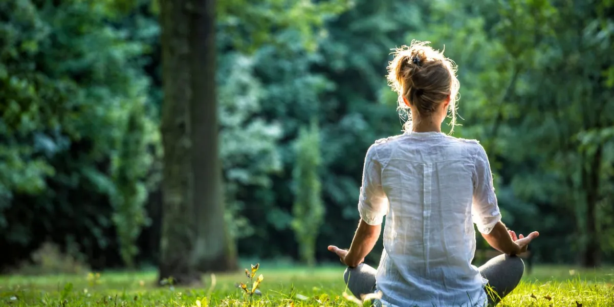 young blonde woman meditating in the park