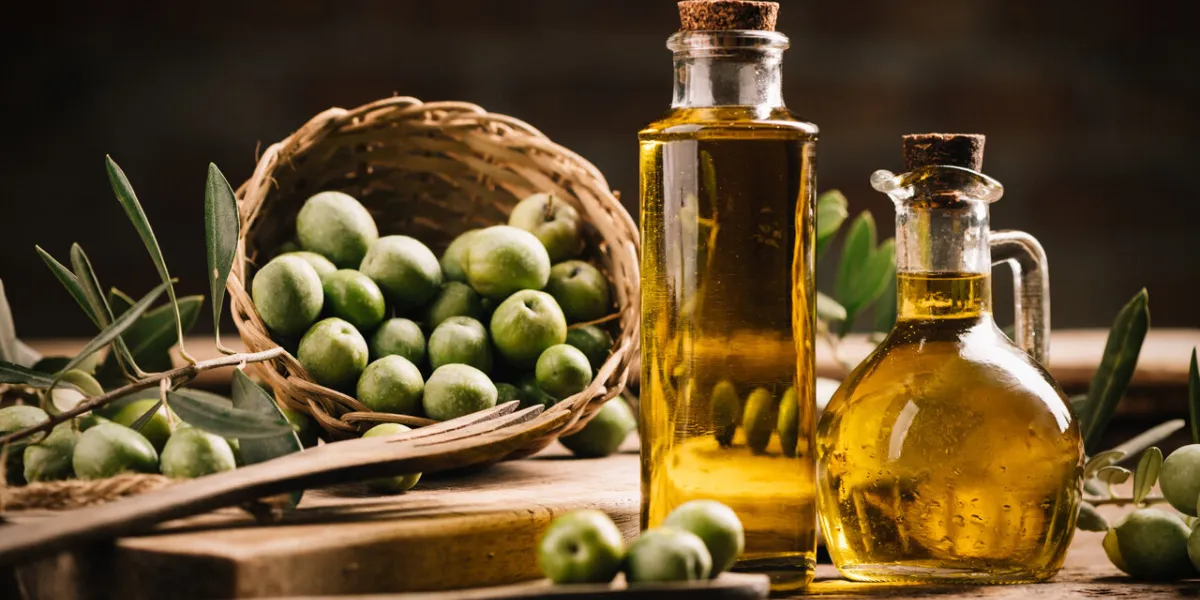 olive oil with fresh olives on rustic wood close up