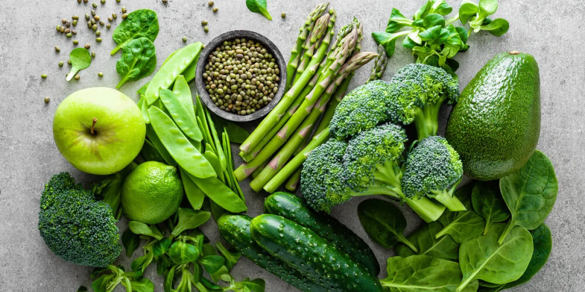 healthy vegetarian food concept background, fresh green food selection for detox diet, raw broccoli, apple, cucumber, spinach, peas, asparagus, avocado, lime, corn salad and mung bean, view from above, flat lay