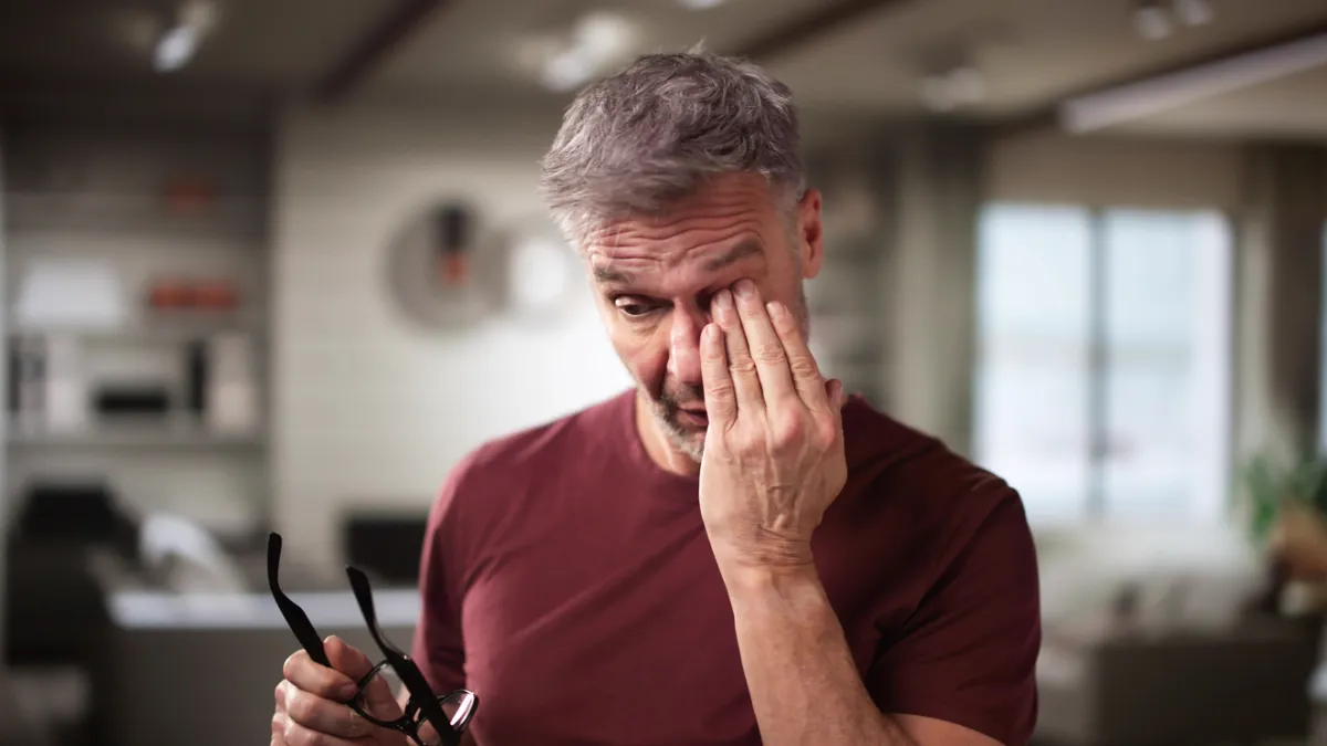 homme qui se frotte l'oeil