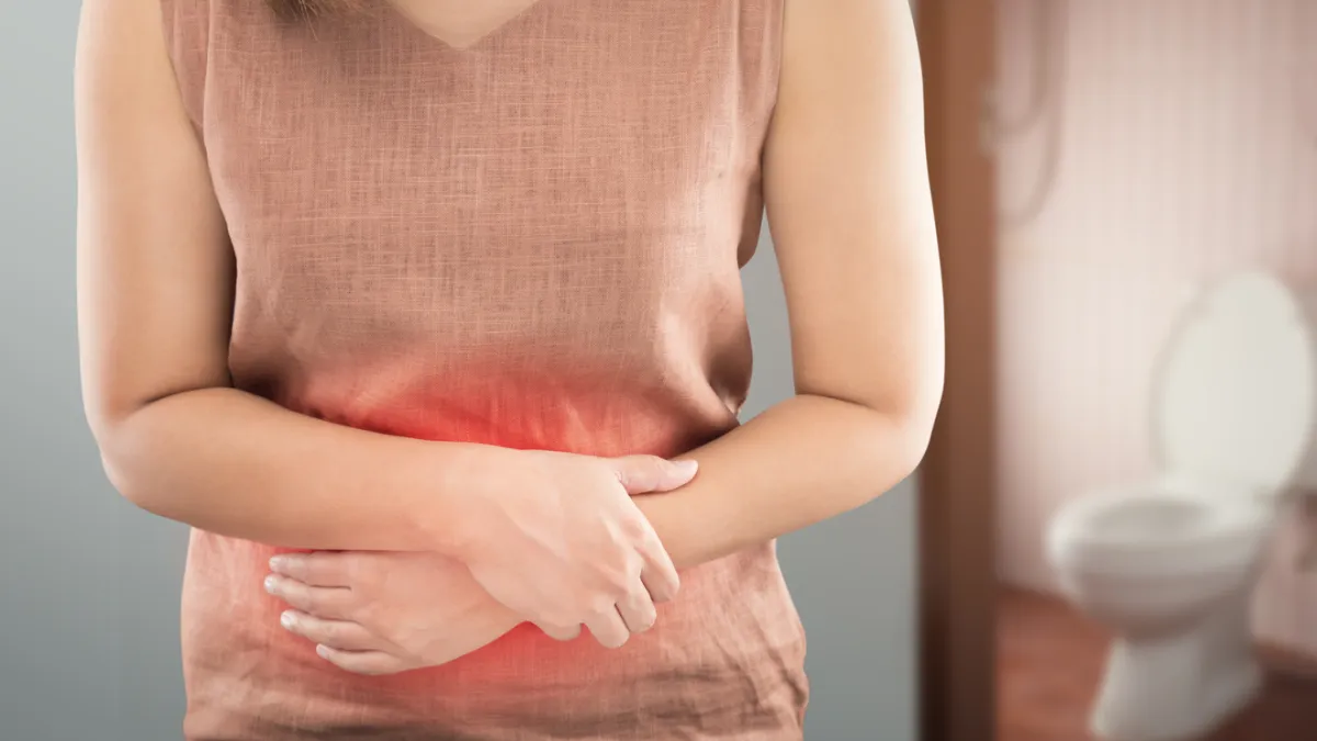 femme qui se tient le ventre devant des toilettes
