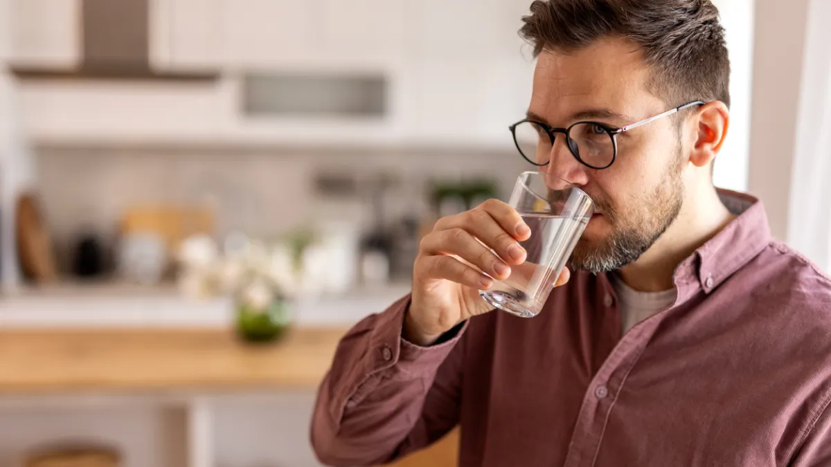 homme qui boit un grand verre d'eau